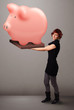 Foto: Young girl holding a huge savings piggy bank Young girl holding a huge savings piggy bank