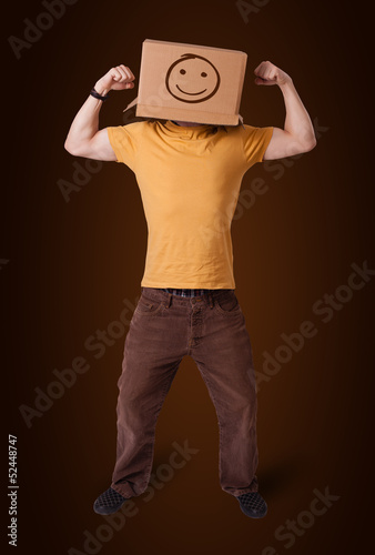 Photo: Young man gesturing with a cardboard box on his head with smiley Young man gesturing with a cardboard box on his head with smiley