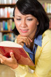 Photo: Asian girl in library reading a book Asian girl in library reading a book