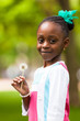 Outdoor portrait of a cute young black girl holding a dandelion