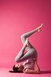 young woman doing bicycle exercise studio shot pink background
