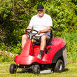 Senior man driving a red lawn mower (tractor)