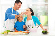 Photo: loving husband feeding wife a piece of tomato while cooking loving husband feeding wife a piece of tomato while cooking