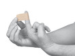 Hand putting Adhesive Bandage on man finger.
