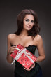 Portrait of brunette beautiful woman with gift on grey