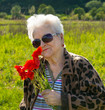 Elderly woman in sunglasses with bunch of poppies