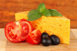 Cheese,basil and vegetables on wooden background