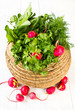A bunch of fresh vegetables in a bowl wicker basket on white woo