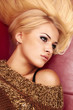 beautiful blond woman laying on a red leather sofa