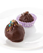 Delicious chocolate candies with colorful shavings on white back