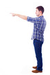young casual man pointing towards copyspace, isolated on white b