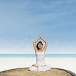 Asian woman practicing yoga at beach