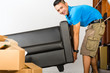 Young asian man lifting a couch