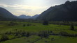 aerial view of meadow and stream with alpine mountains