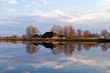 Dutch farmhouse by river before sunset