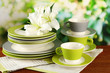 Empty plates and cups on wooden table on green background