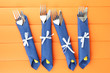 Forks and knives wrapped in blue paper napkins,