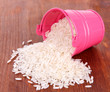 Overturned bucket with grains on wooden background