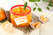 Orange jam with zest and tangerines, on white wooden table