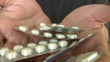 A male hand holding a pack of  pills.
