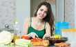  housewife cuts tomato at  kitchen