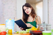   beautiful woman reads cookbook for recipe