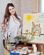 Happy young woman paints on canvas with oil paints