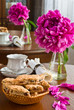 White cup of tea and biscuits and peony