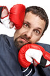 Close-up young businessman struck by hands in boxing gloves
