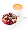 Fruit fresh crumble dessert in a white bowl with a cup of tea  o