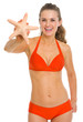 Smiling young woman in swimsuit showing starfish