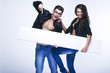 Fashionable happy couple holding white board
