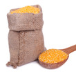 Corn groats in a bag and a wooden spoon isolated on a white