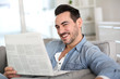 Photo: Relaxed guy at home reading newspaper Relaxed guy at home reading newspaper