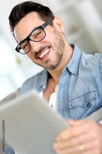 Photo: Middle-aged guy using digital tablet at home Middle-aged guy using digital tablet at home