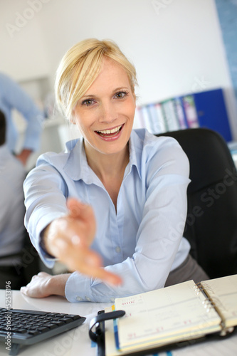 Photo: Businesswoman giving handshake to client Businesswoman giving handshake to client