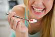 Closeup on spoon with yogurt in hand of smiling teenager girl