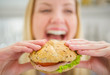 Closeup on burger in hand of smiling teenager girl
