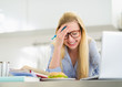 Smiling teenager girl studying in kitchen