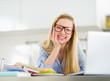 Photo: Happy young woman studying in kitchen Happy young woman studying in kitchen