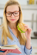 Photo: Young woman eating sandwich and reading book Young woman eating sandwich and reading book