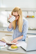 Photo: Young woman drinking coffee while studying in kitchen Young woman drinking coffee while studying in kitchen