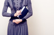 Young beautiful woman in gray vintage dress holding bible