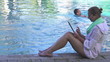 Woman with tablet sit by the pool, super slow motion
