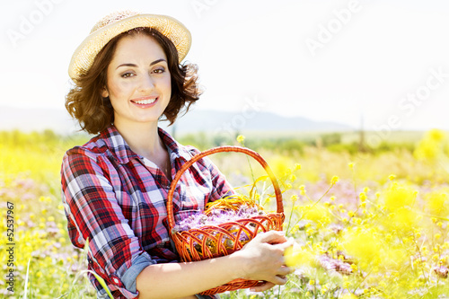 Photo: Portrait of young woman holding basket with flowers outside Portrait of young woman holding basket with flowers outside