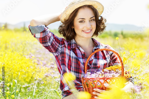 Photo: Portrait of young woman holding basket with flowers outside Portrait of young woman holding basket with flowers outside