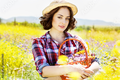 Photo: Portrait of young woman holding basket with flowers outside Portrait of young woman holding basket with flowers outside