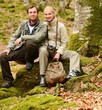 Foto: Happy smiling travellers couple sitting on a rock Happy smiling travellers couple sitting on a rock