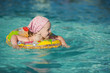 Little cheerful girl swimming in the pool