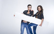 Fashionable lovely couple holding white board